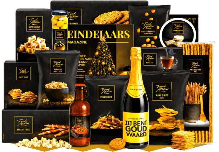 Kerstpakket in zwart en goud met snacks, pasta, saus en een fles sparkling apple